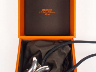 Vente aux enchères HERMES. Pendentif "Lima" en argent, cordon cuir noir. Dans sa boîte et