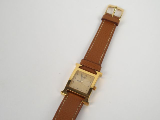 HERMES. Montre H femme, boitier or et bracelet chocolat. On y joint un