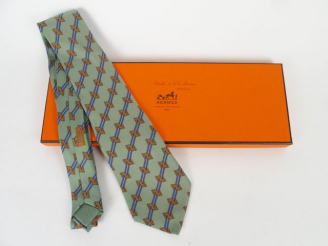 Vente aux enchères HERMES. Cravate en soie à décor de têtes de chevaux et de rayures sur 