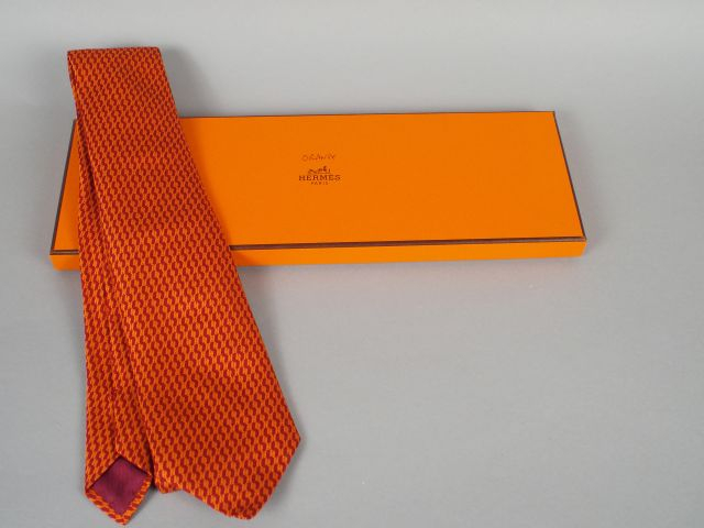 HERMES. Cravate en soie orange et bordeaux