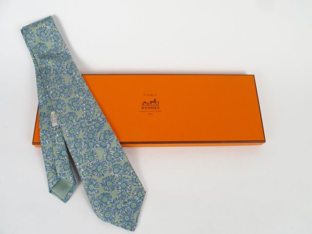 HERMES. Cravate en soie à décor de fleurs bleues sur fond vert amande