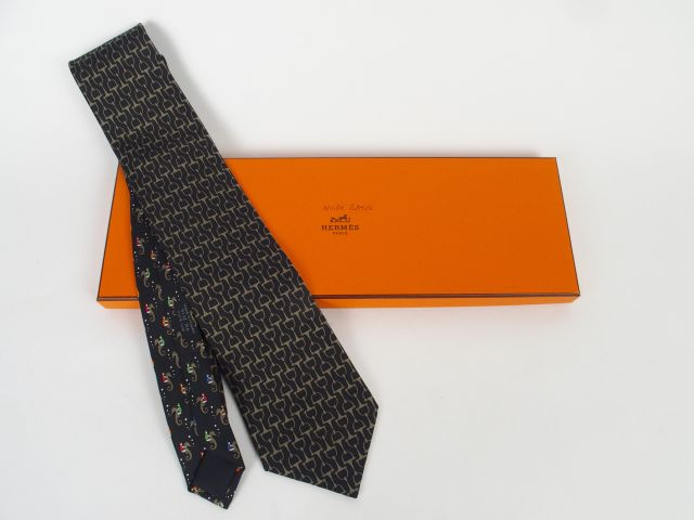 HERMES. Cravate en soie, à décor de mors sur fond noir, et d'hippocamp
