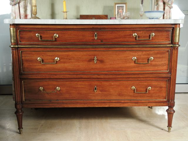 Commode Louis XVI en acajou, pieds toupie, ouvrant à trois tiroirs sur