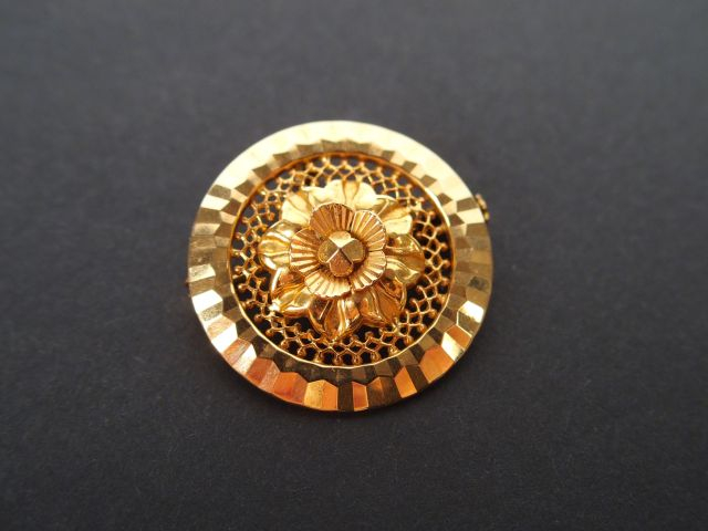 Broche ronde en or jaune, décor ajouré et fleur. Poids: 3,9gr