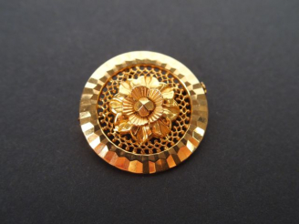 Vente aux enchères Broche ronde en or jaune, décor ajouré et fleur. Poids: 3,9gr