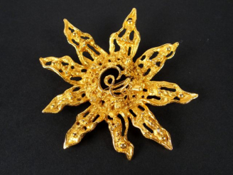 Vente aux enchères CHRISTIAN LACROIX. Broche en métal doré en forme de tournesol stylisé.