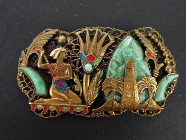 Broche en métal doré ajouré, décor en pierre dure de scène égyptienne,