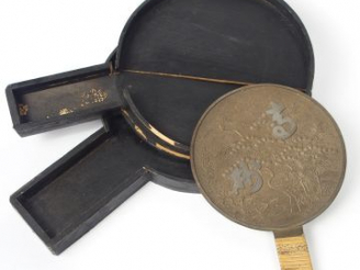 Vente aux enchères Miroir  à main circulaire en bronze patiné à décor en léger relief de 