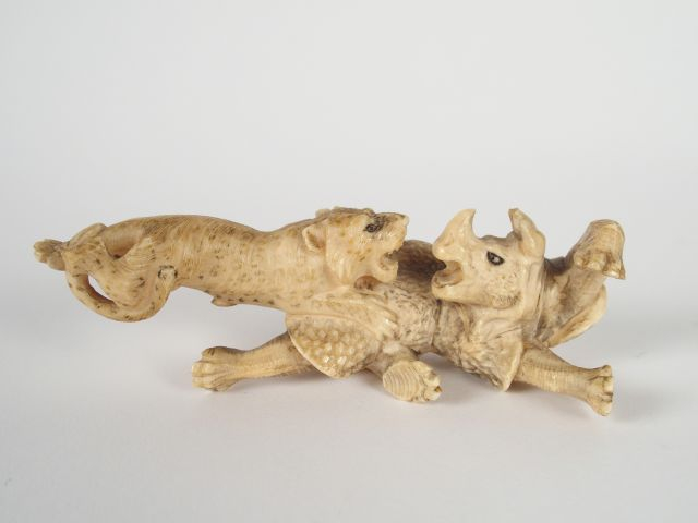 Okimono en ivoire d’éléphant sculpté  représentant un rhinocéros attaq