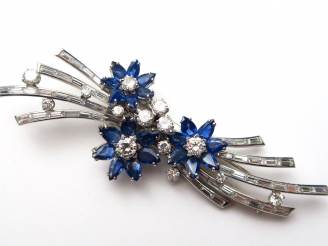 Vente aux enchères GUBELIN. Broche monture or blanc en diamants et saphirs à décor de fle