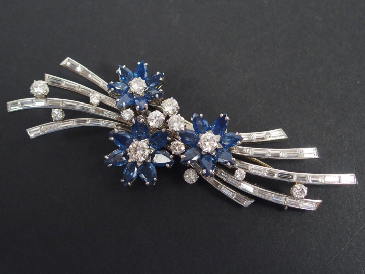 GUBELIN. Broche monture or blanc en diamants et saphirs à décor de fle
