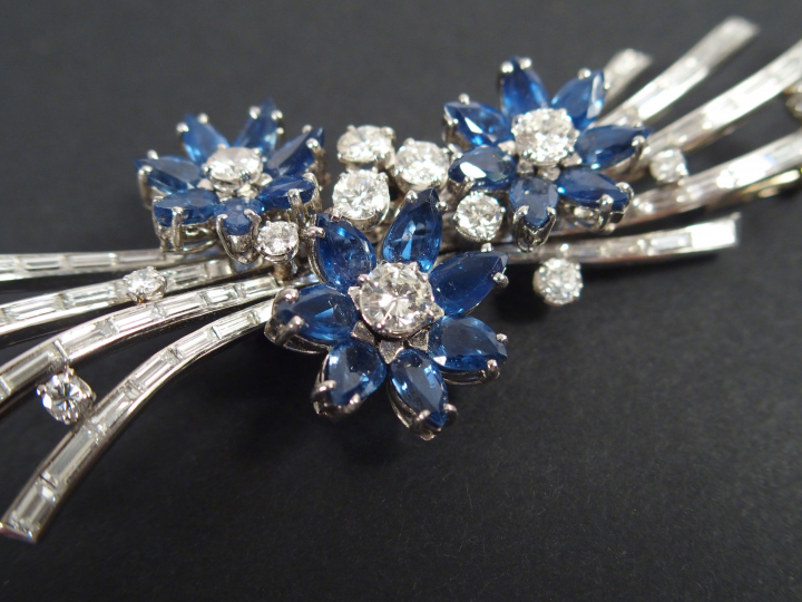 GUBELIN. Broche monture or blanc en diamants et saphirs à décor de fle