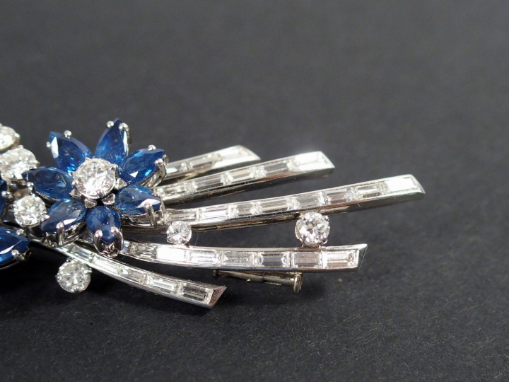 GUBELIN. Broche monture or blanc en diamants et saphirs à décor de fle
