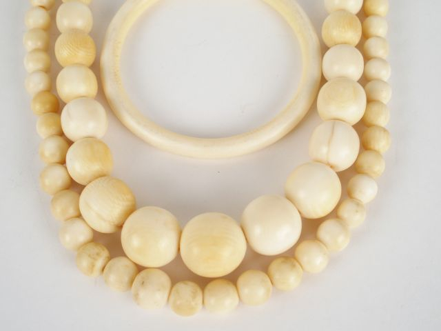 2 colliers en perles d'ivoire disposées en chute (64 cm environ chacun