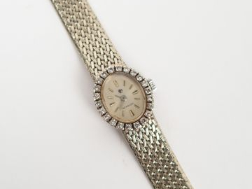 ADER. Montre femme en or blanc, boitier rond entourage de brillants et