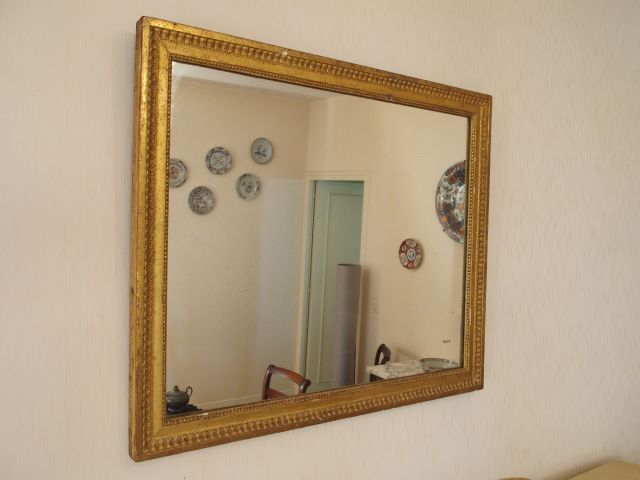 Glace Louis XVI en bois sculpté et doré, à décor de perles et de rais-