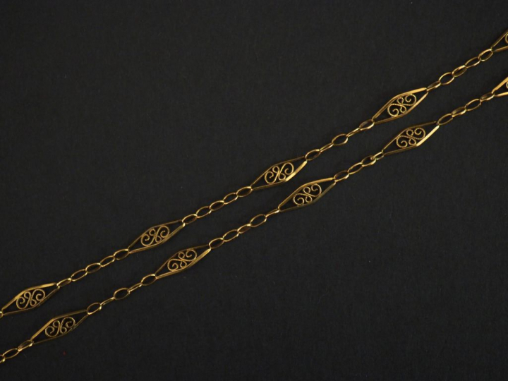 Collier souple en or jaune, composé de maillons ajourés et fligranés. 