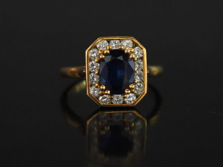 Bague en or jaune, saphir taille émeraude, entourée de 14 brillants.  
