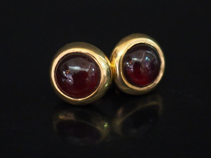 Paire de perce oreilles en or et pierre rouge en cabochon. Diam. 1 cm 