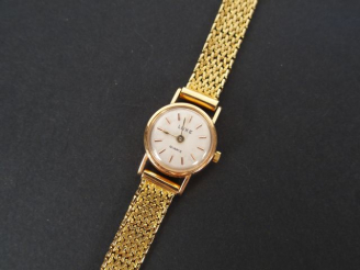 Vente aux enchères LUXE. Montre de dame, boitier rond et bracelet semi rigide en or jaune