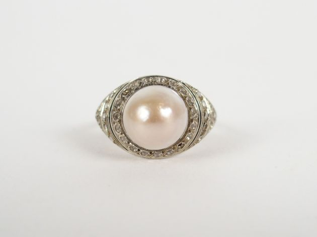Bague monture platine, pavée de roses et surmontée d'une perle mabée. 