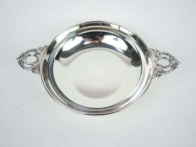 Plat creux à anses en métal argenté, anses ajourées et feuillagées.