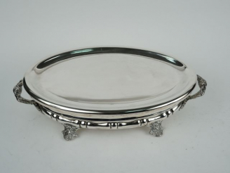 Vente aux enchères Chauffe plat ovale en métal argenté, quatre pieds à décor de pampres