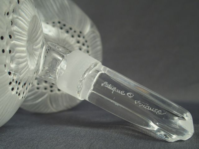 LALIQUE. Flacon en verre, bouchon en forme de fleurs.Signé. H. 17 cm