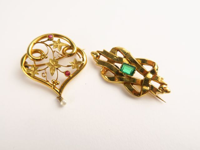 Deux broches en or, l'une à décor de ruban, rehaussée d'une pierre ver