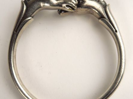 HERMES. Bracelet jonc en métal argenté, à décor de deux têtes de cheva