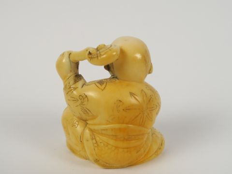 Okimono en ivoire représentant un caraco tenant une pêche et un lingzh