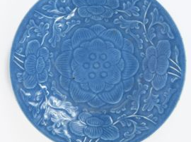Plat rond en porcelaine émaillée bleu lavande, à décor floral moulé so