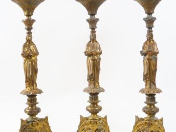 Suite de trois pique-cierges en bronze, à décor d'archanges (manques).