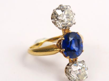 Bague ornée en ligne de deux diamants taille coussin et d'un saphir au