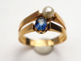 Vente aux enchères 	Bague ornée d’un saphir et d’une perle en pendant. Monture en or jaun