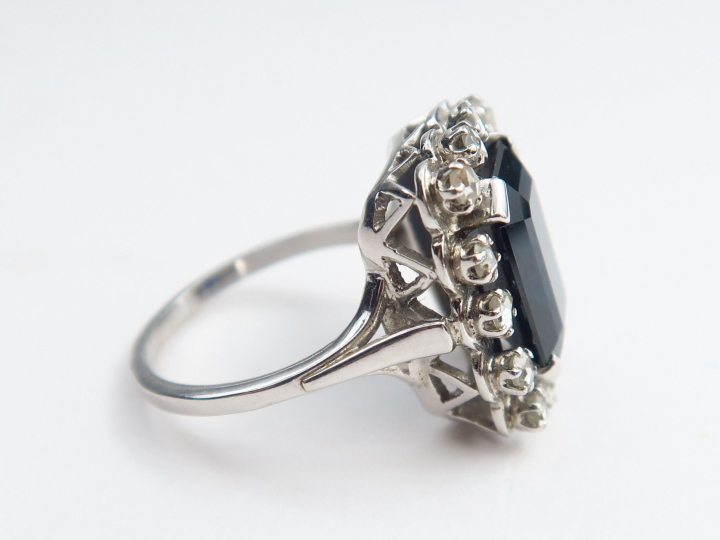 Bague en platine ornée d’un saphir, dans un entourage de petits brilla