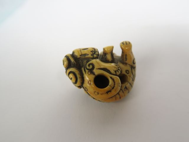 Netsuke en ivoire représentant un shishi couché, la tête vers l’arrièr