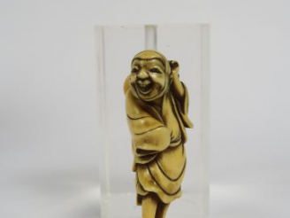 Vente aux enchères Netsuke en ivoire représentant un personnage souriant, debout, un fich