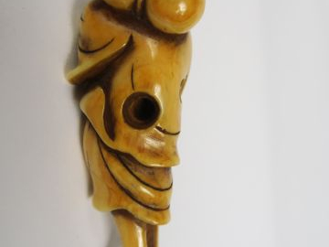 Netsuke en ivoire représentant un personnage souriant, debout, un fich