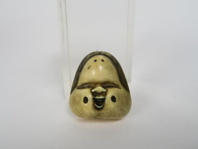 Netsuke en ivoire et rehauts bruns représentant un masque d’Okame, le 