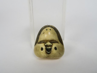 Vente aux enchères Netsuke en ivoire et rehauts bruns représentant un masque d’Okame, le 