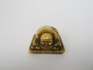 Vente aux enchères Netsuke en ivoire et rehauts bruns représentant un homme endormi sur u