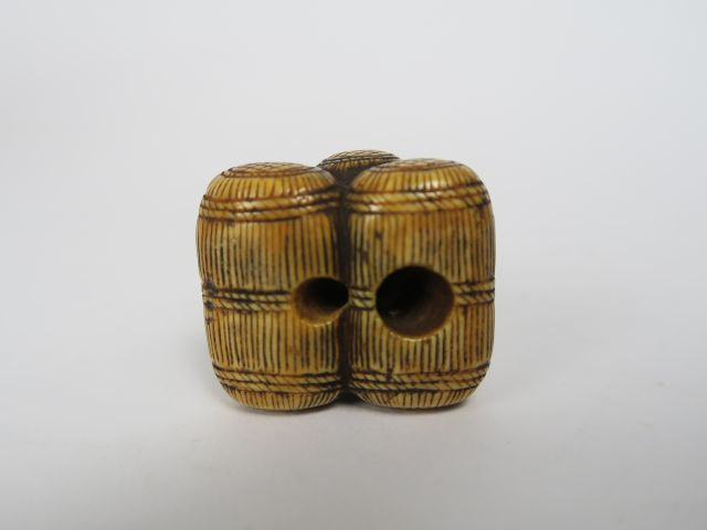 Netsuke en ivoire et rehauts bruns représentant trois balles de riz su
