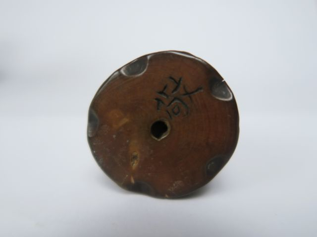 Netsuke en bois représentant un shishi assis, la patte posée sur son p