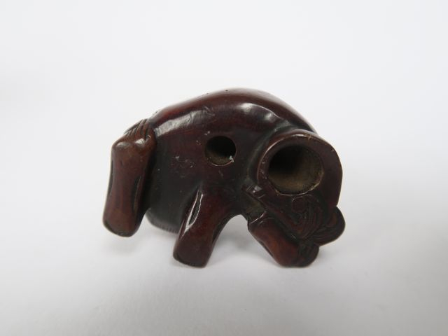 Netsuke en bois représentant un shishi couché, tenant une balle mobile