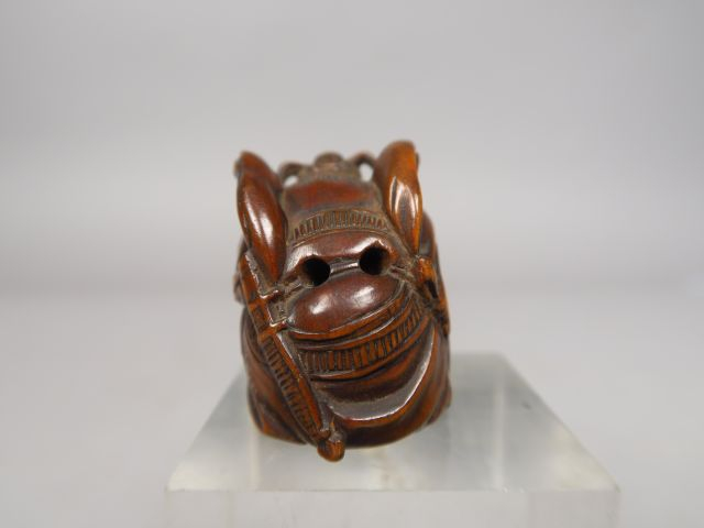 Netsuke en bois représentant Shoki plaquant au sol un grand chapeau so