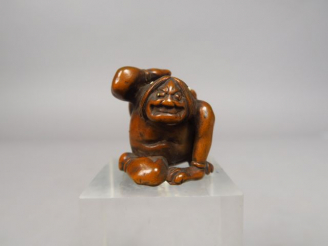 Vente aux enchères Netsuke en bois représentant un oni assis, retenant de sa main droite,