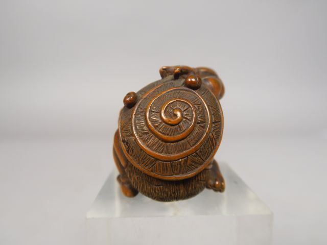 Netsuke en bois représentant un oni assis, retenant de sa main droite,