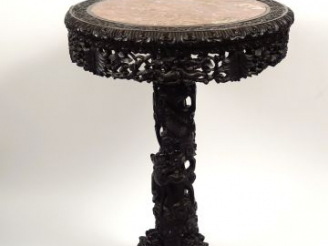 Vente aux enchères Guéridon en bois de fer reposant sur trois pieds griffés, sculpté d'un