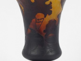 Vente aux enchères DAUM. Vase cornet en verre, à décor de fleurs mauves sur fond brun et 